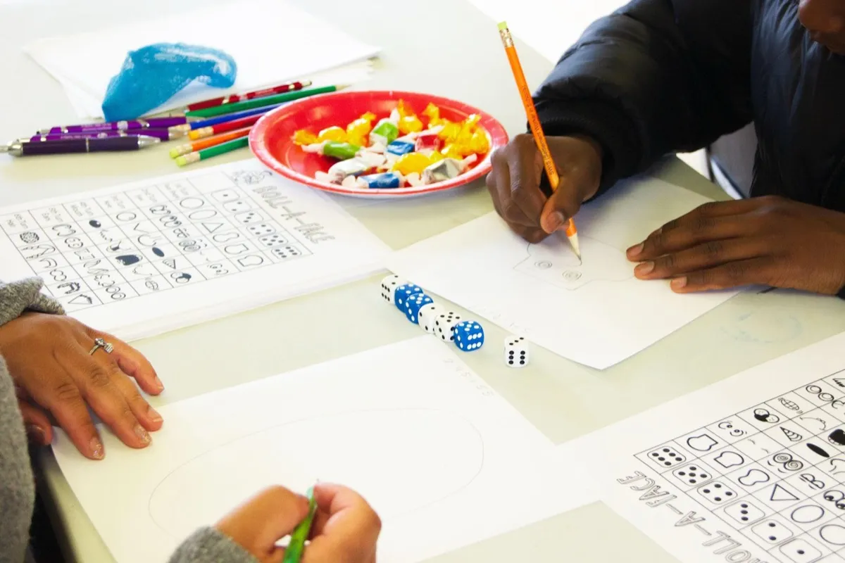 Youth drawing and playing educational games at a day program activity table